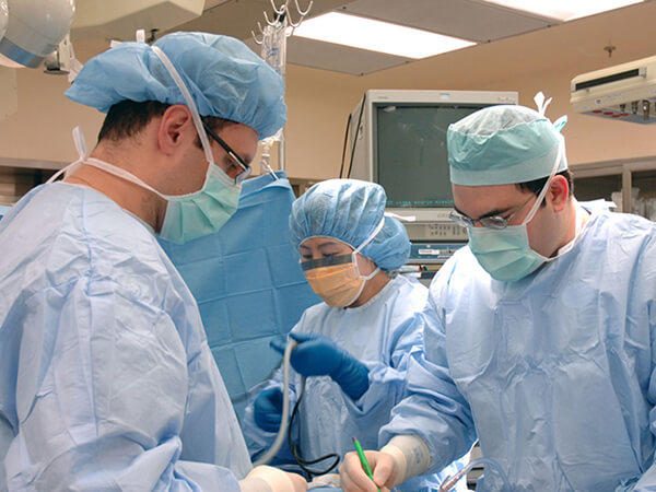 Équipe de chirurgie en tenue de bloc opératoire. Photographie documentaire du National Cancer Institute.