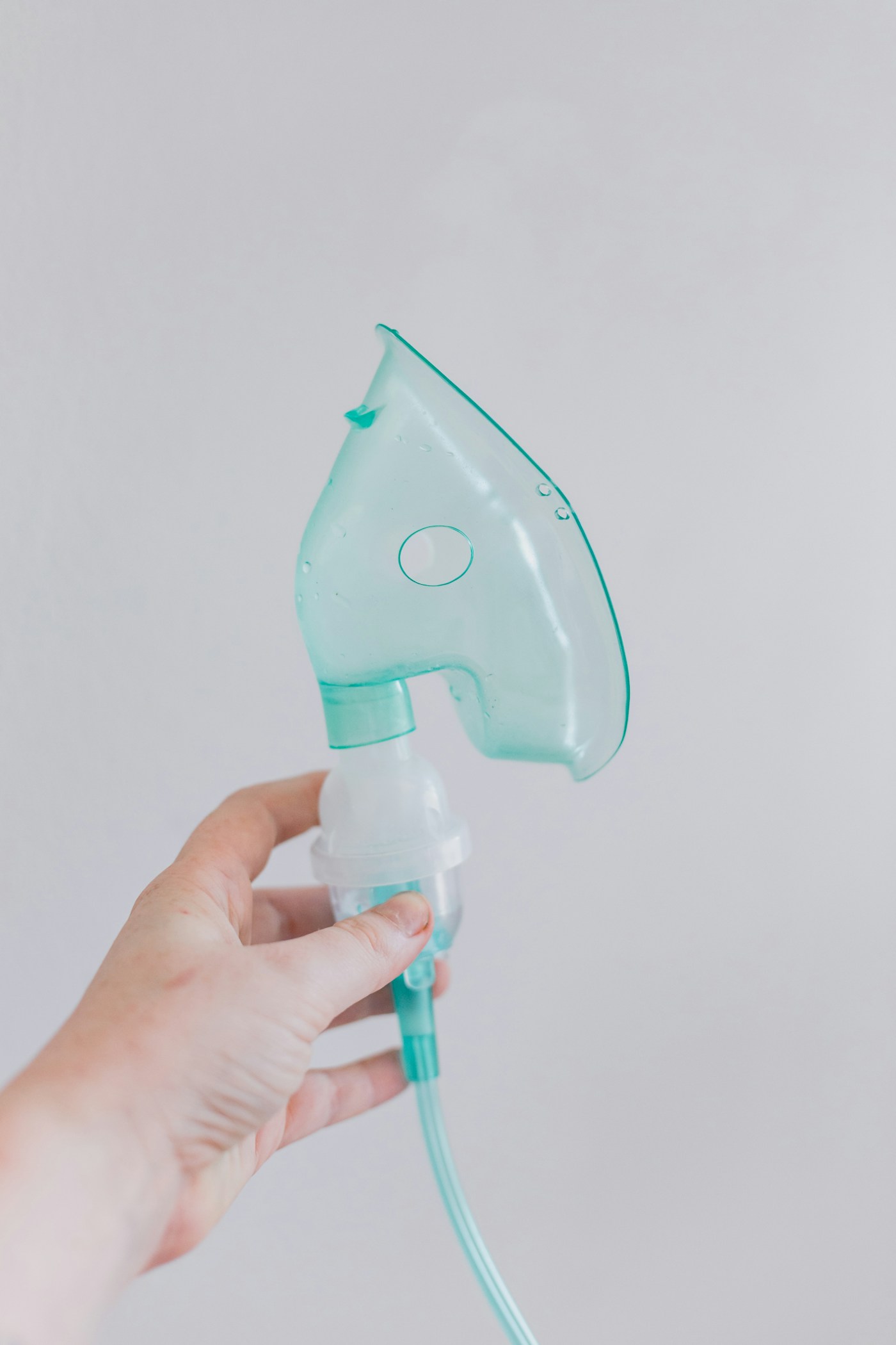 Masque et tubulure d’un dispositif respiratoire tenus en main. Photographie d’illustration de l’administration respiratoire, sans recommandation de matériel.