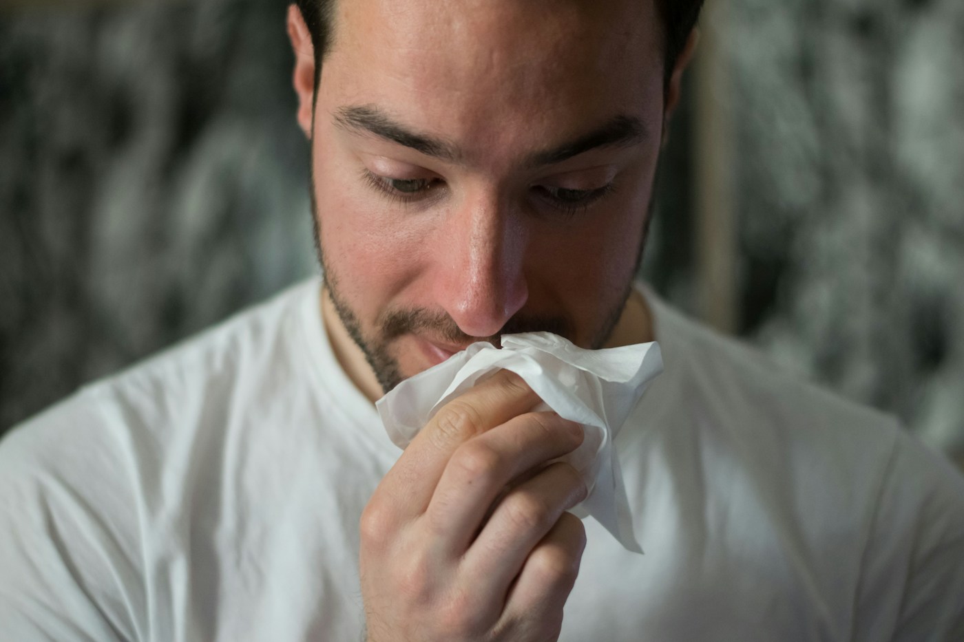 Personne utilisant un mouchoir. Illustration des symptômes nasaux, sans allergie diagnostiquée.